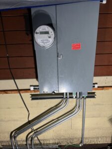 A gray electrical panel with an electric meter and an 