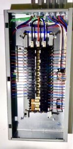 An open electrical panel shows multiple circuit breakers, organized wiring, and labeled connections.