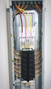 Electrical breaker panel with multiple colored wires connected to circuit breakers and bus bars inside a metal enclosure.