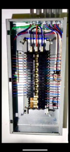 An open electrical panel showing multiple circuit breakers, neatly organized wiring, and labeled connections.